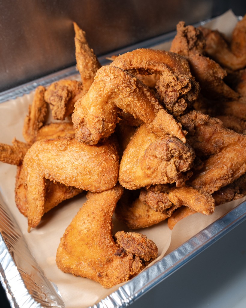 Crispy golden fried chicken piled high in a foil-lined tray